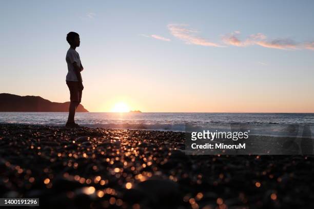 boy walking by the seaside in morning glow - sea club ストックフォトと画像
