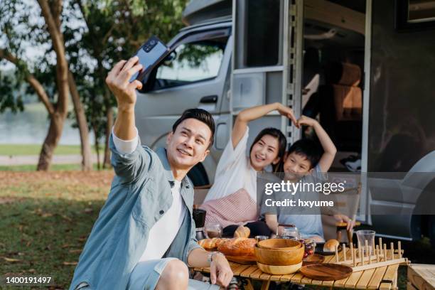 asian family taking selfie photo during caravan picnic vacation - trailer park imagens e fotografias de stock