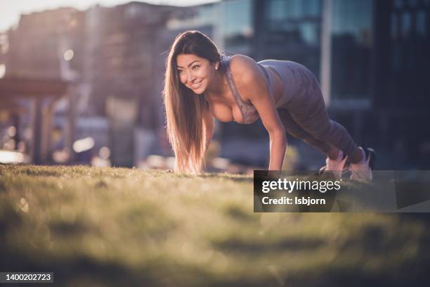 fit woman doing a push ups outdoors - sportbeha stockfoto's en -beelden