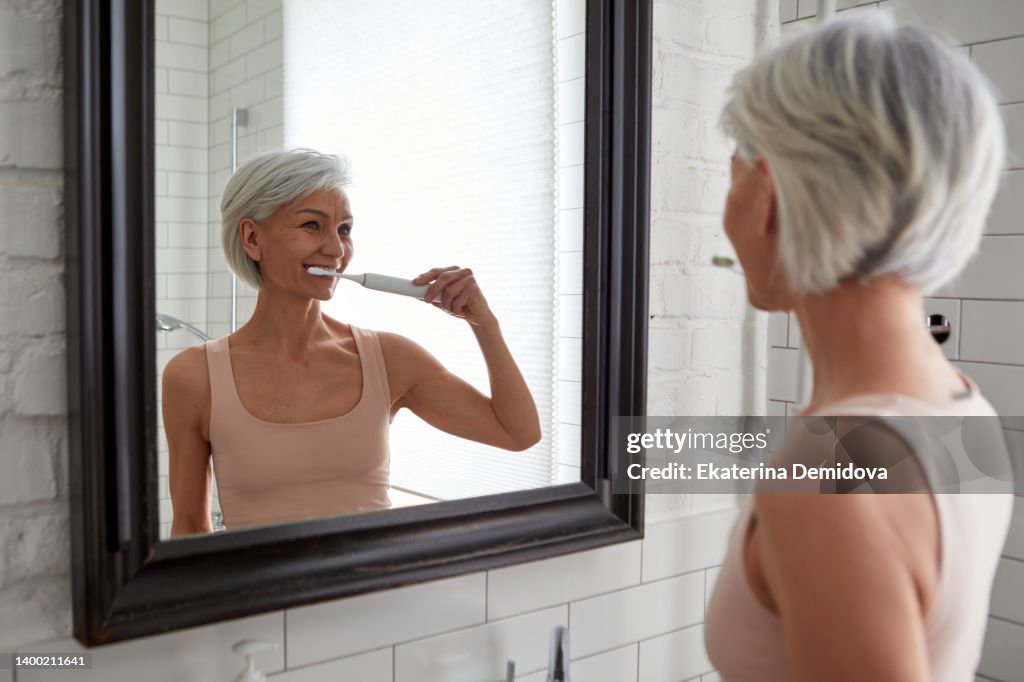 Elderly female brushing teeth at home