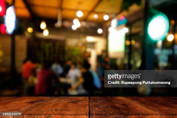 wood table top with blur of lighting in night cafe. celebration concept - bar cafeteria fotografías e imágenes de stock