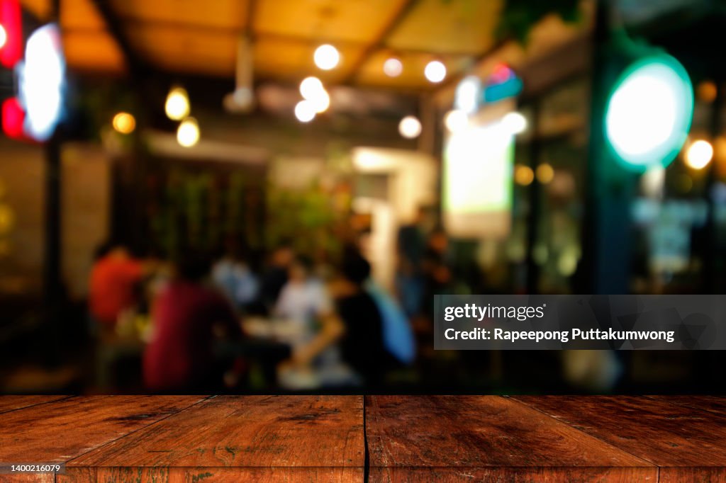 Wood table top with blur of lighting in night cafe. Celebration concept