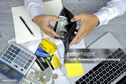 Man hand opening wallet, debt expense bills monthly and credit card at the table in home office , managing payroll,money risk financial concept