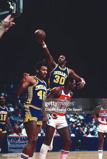 George McGinnis of the Indiana Pacers lays the ball up over Elvin Hayes of the Washington Bullets during an NBA basketball game circa 1981 at the...