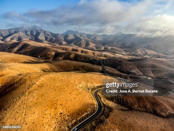 aerial view, curvy mountain road in a volcanic desert landscape at sunset. - desert mountain range stock pictures, royalty-free photos & images