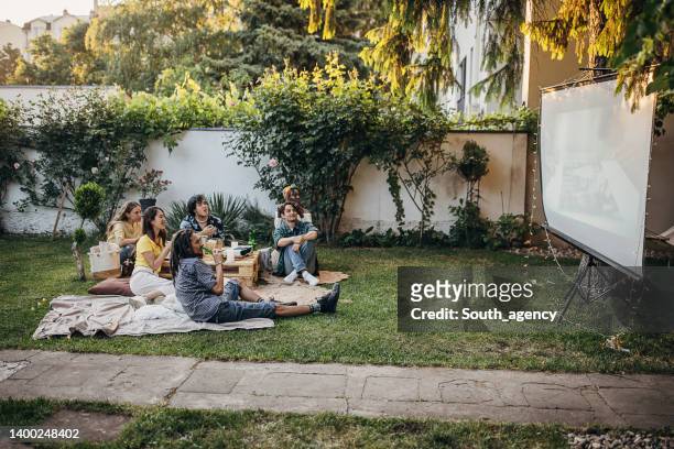 friends watching movie on the video projector in the backyard garden - backyard movie stock pictures, royalty-free photos & images
