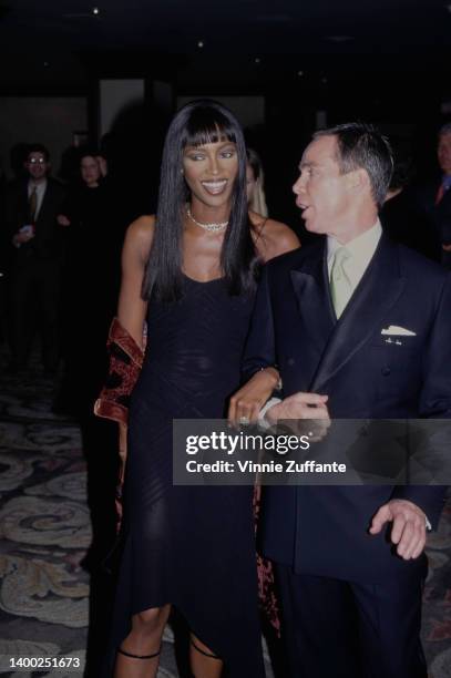 British fashion model Naomi Campbell, wearing a black dress, and American fashion designer Tommy Hilfiger attend the 5th Annual Race To Erase MS...