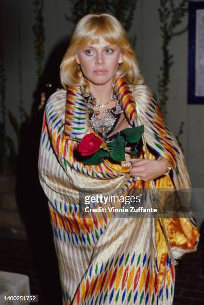Swedish actress and singer Britt Ekland, holding a red rose while wrapped in a multi-coloured shawl, United States, circa 1982.
