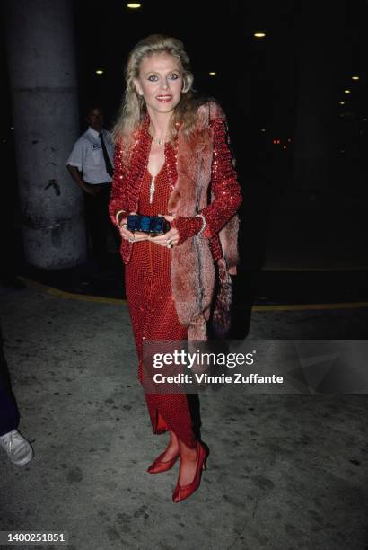 Swedish actress and singer Britt Ekland, holding a blue box, wearing a red sequin jacket over a red sequin dress, United States, circa 1985.