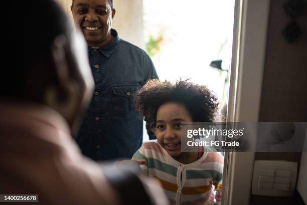 father and daughter being greeted by real estate agent (or mother opening the front door to his daughter and husband) - family front door stock pictures, royalty-free photos & images