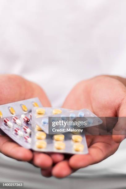 young man holding multiple pill blisters in his hands. - hand holding several pills photos et images de collection
