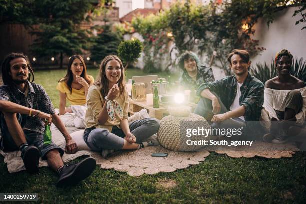 group of friends having a gathering, watching a movie on projector in the garden and hanging out - projection film outdoor stock pictures, royalty-free photos & images