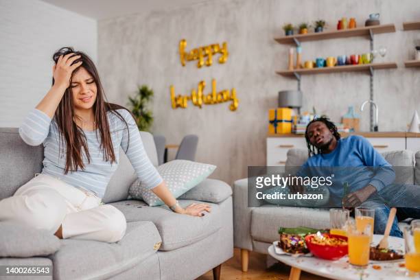 two hangover friends waking up after a birthday party - house after party stockfoto's en -beelden