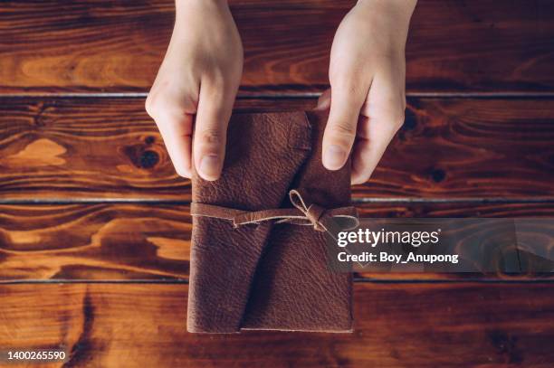 high angle view of someone hands holding a book with leather cover on wooden table. - libro cerrado fotografías e imágenes de stock