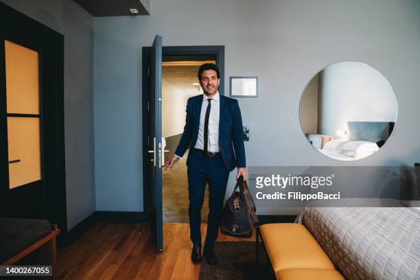 un homme d’affaires entre dans une chambre d’hôtel - business travel photos et images de collection