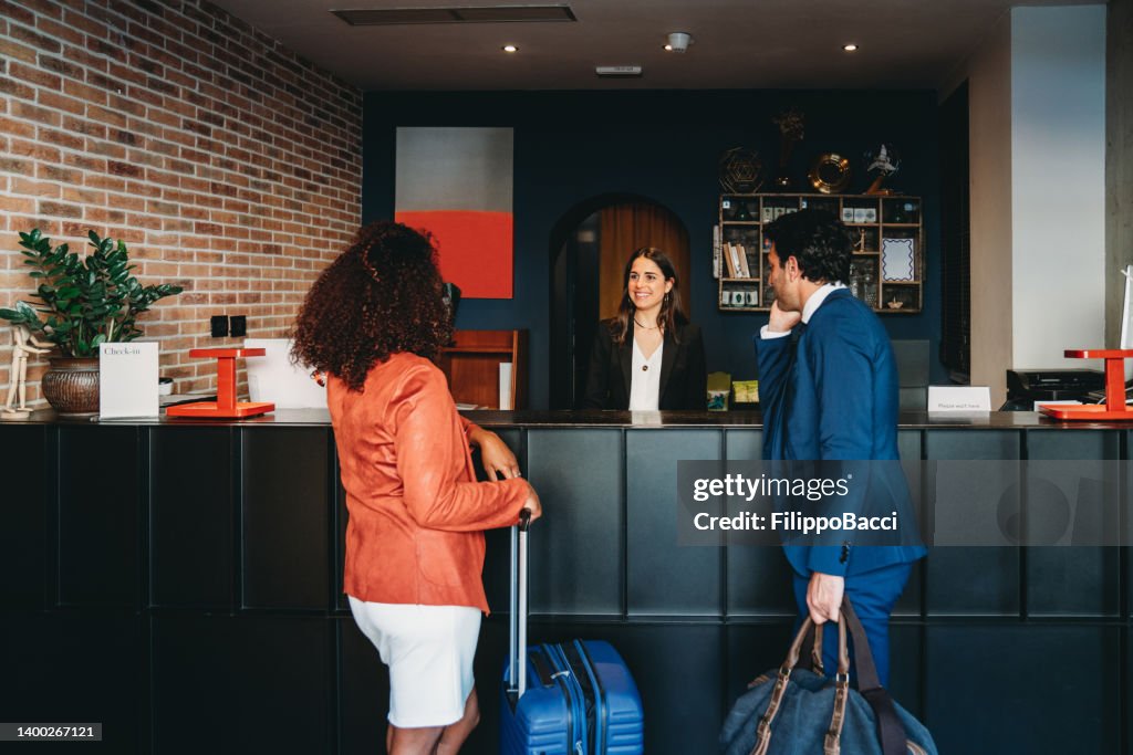 A couple of business people are checkin-in at the hotel lobby