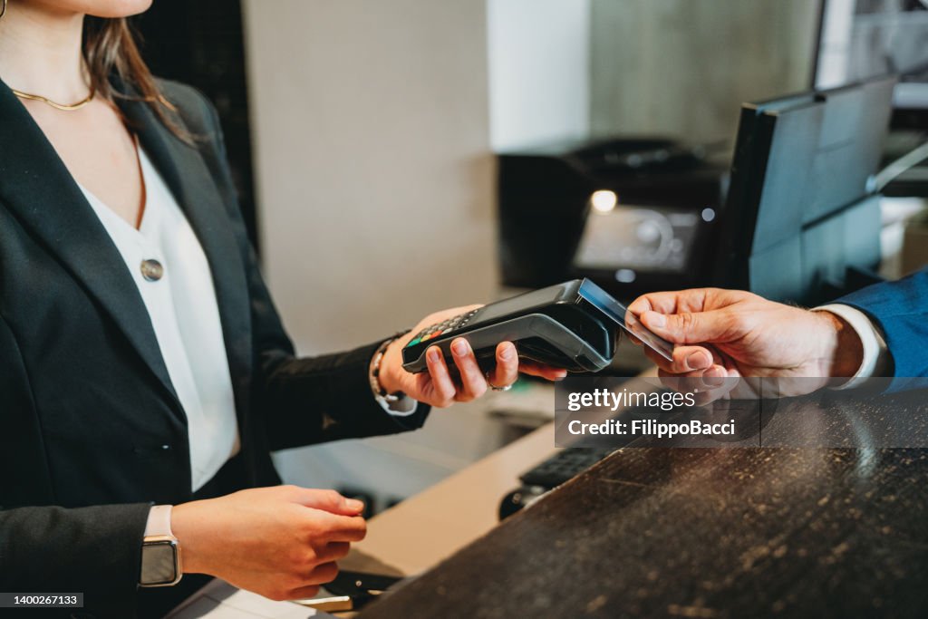 Un hombre de negocios está pagando con tarjeta de crédito en la recepción del hotel