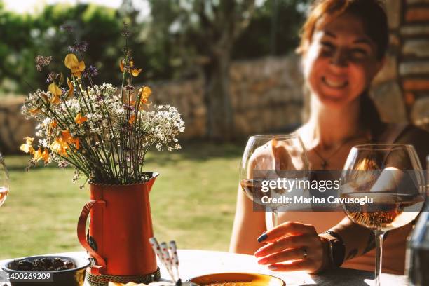 woman sitting outside at the table enjoying glass of wine. - white rose garden stock pictures, royalty-free photos & images