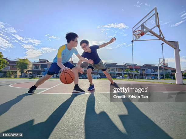 père et fils chinois asiatiques s’amusant, jouant au basket-ball en plein air pendant le week-end le matin - father son challenge round two photos et images de collection