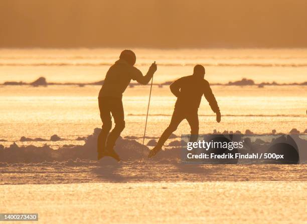 silhouette of two people snowshoeing against winter sky during sunset - rörelse stock-fotos und bilder