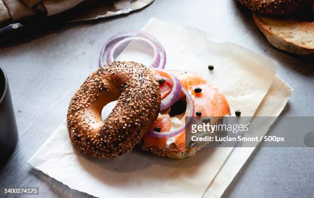 close-up of lox bagel with onions on paper sheet - räucherlachs stock-fotos und bilder
