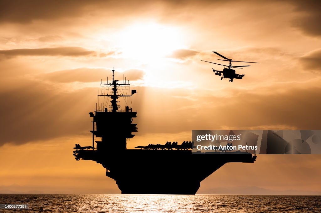 Aircraft carrier at sunset in the sea