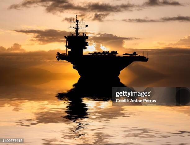 aircraft carrier at sunset in the sea - flotte stock-fotos und bilder