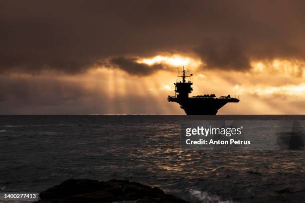 aircraft carrier at sunset in the sea - 海軍 ストックフォトと画像
