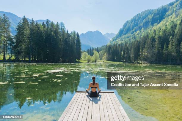 young woman practices yoga on lakeside dock - slovenia mountains stock pictures, royalty-free photos & images