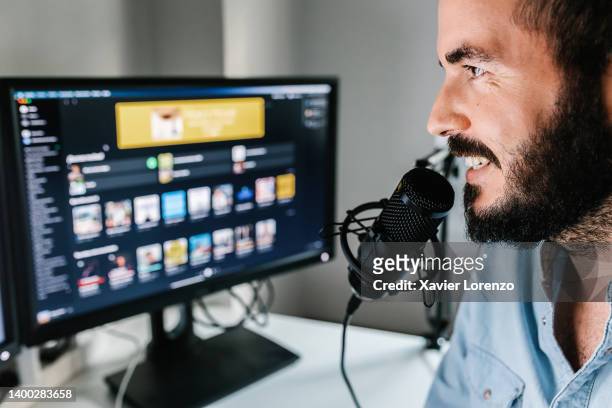 young adult man making audio podcast from home studio - content creator recording radio show using professional microphone at small broadcast studio - live broadcast stock pictures, royalty-free photos & images