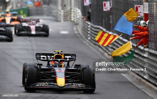 Track marshals wave their flags as Race winner Sergio Perez of Mexico driving the Oracle Red Bull Racing RB18 passes them during the F1 Grand Prix of...