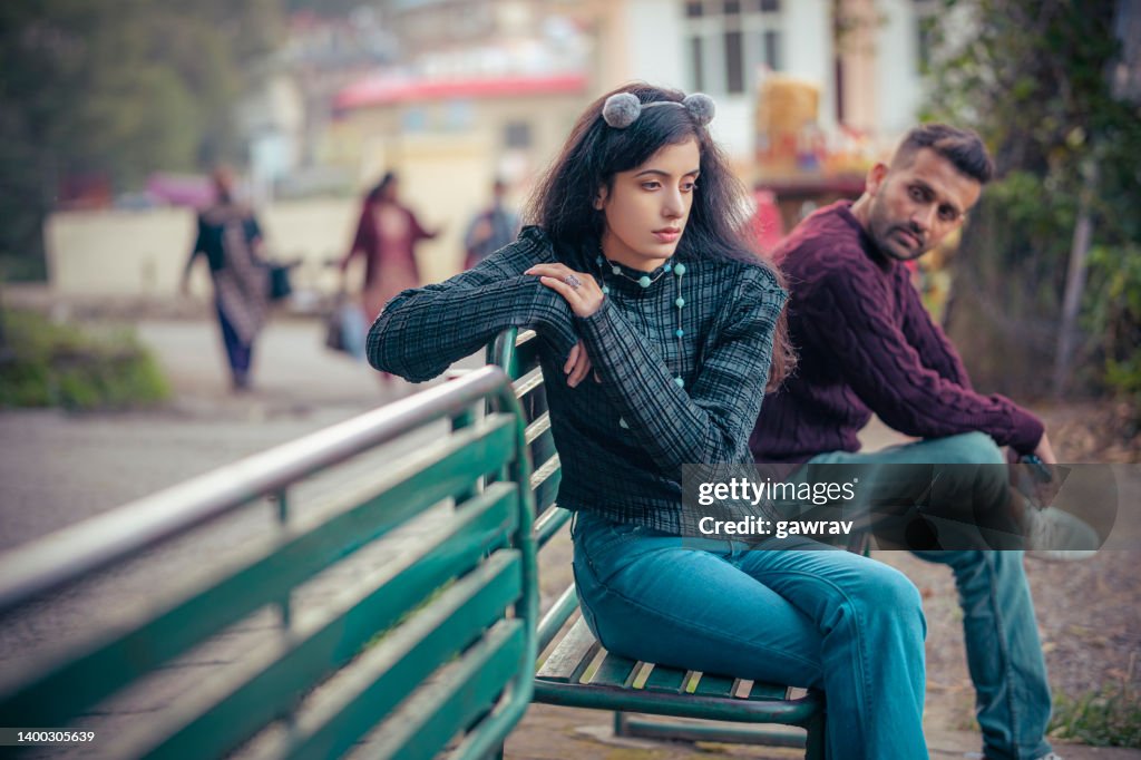 Sad young woman and a man sits together o a park bench.