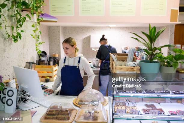 young woman working in small coffee and sweets shop - deeltijdbaan stockfoto's en -beelden