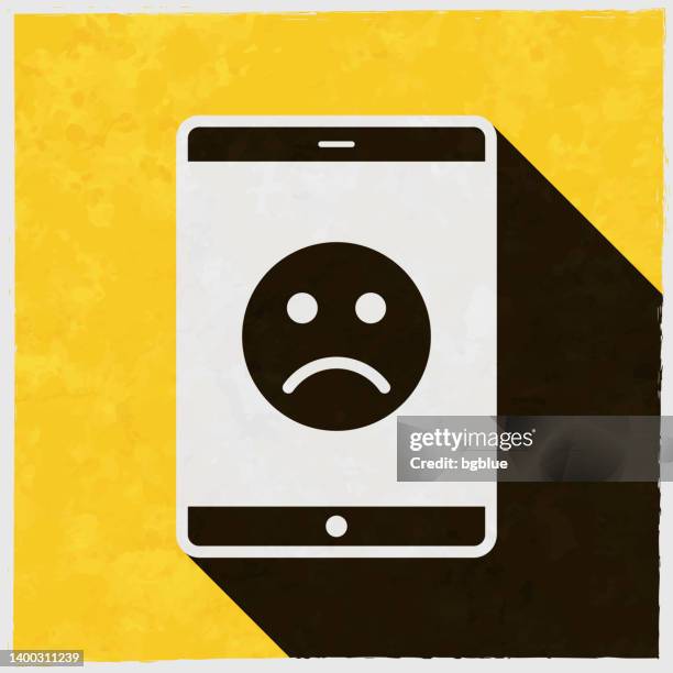 tablet pc with sad emoji. icon with long shadow on textured yellow background - disappointing phone stock illustrations