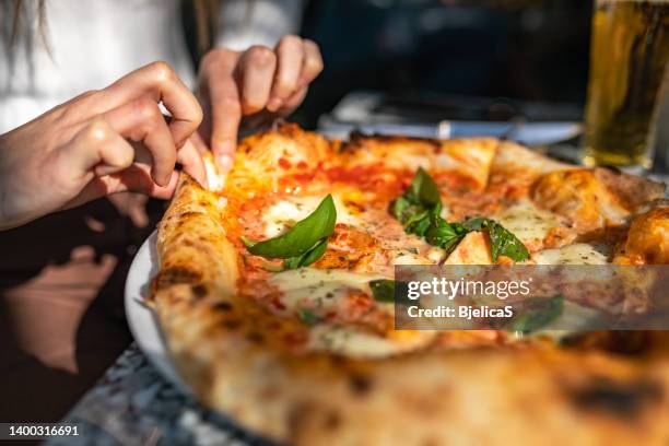 unrecognizable woman taking a slice of pizza - pizza stockfoto's en -beelden