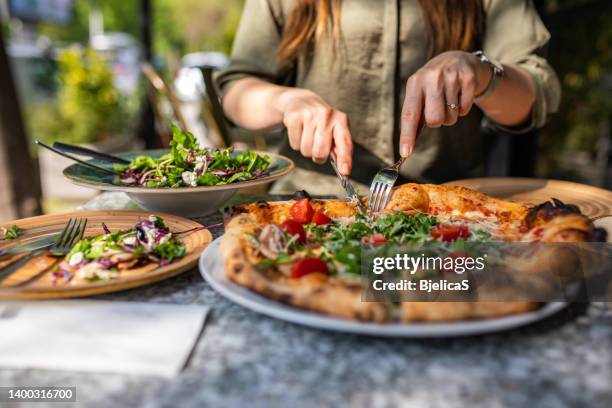 mulher irreconhecível comendo pizza em restaurante - pizzeria - fotografias e filmes do acervo