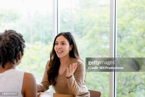 meeting in cafe, mid adult woman shares with unrecognizable friend - performance evaluation stock pictures, royalty-free photos & images