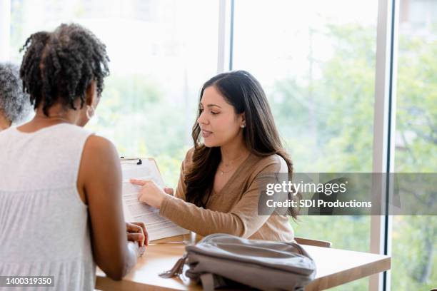 meeting in cafe, businesswoman explains paperwork to client - performance evaluation stock pictures, royalty-free photos & images