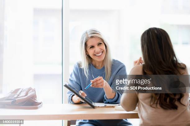 mature female financial advisor meets with unrecognizable female client - employee review imagens e fotografias de stock