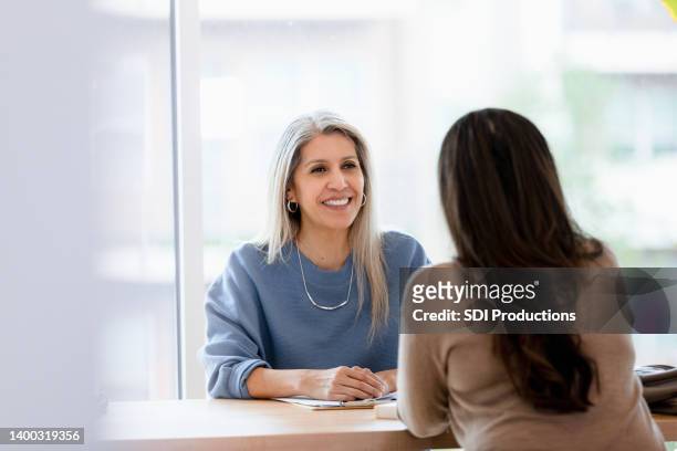 unrecognizable mid adult woman meets with boss for yearly evaluation - performance evaluation stock pictures, royalty-free photos & images