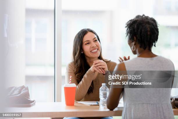 female manager smiles while listening to female job applicant - employee review imagens e fotografias de stock