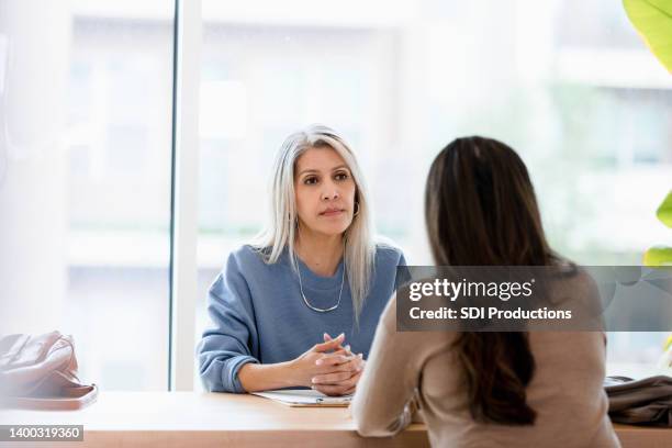 serious businesswoman listens to unrecognizable female client - serious stockfoto's en -beelden