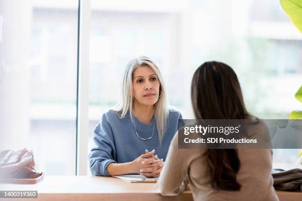 serious businesswoman listens to unrecognizable female client - allvarlig bildbanksfoton och bilder