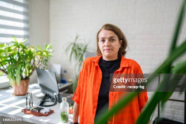 portrait of businesswoman in her environmentalist green office - reusable water bottle office stock pictures, royalty-free photos & images