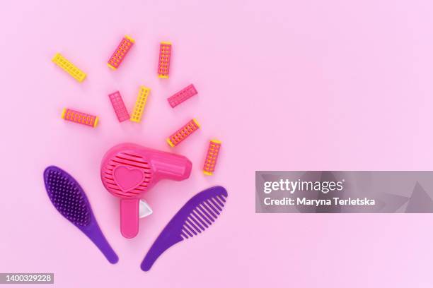 toy hair dryer, hairbrush and curlers on a pink background. master hairdresser. beauty saloon. beauty industry concept. children's girly toys. - hair curlers stockfoto's en -beelden