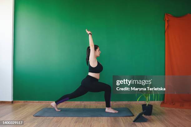 plus size girl doing yoga indoors. sports at home. online training. healthy lifestyle. sports for obese women. fight against line weight. - fat loss training stockfoto's en -beelden