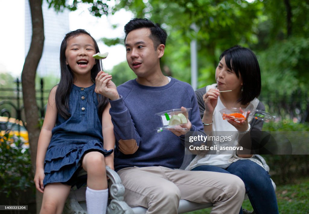 Asian family eating fruit in the park on a bench Taipei