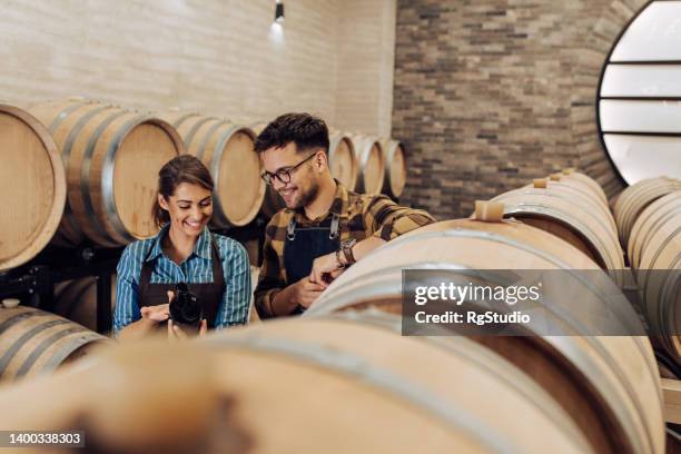 couple of young entrepreneurs checking the quality of the wine in their winery - examining wine stock pictures, royalty-free photos & images