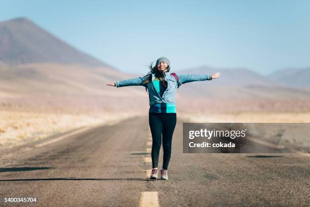 glückliche junge frau, die auf einer leeren straße geht - antofagasta region stock-fotos und bilder