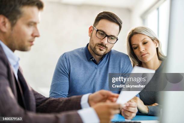 young couple and their insurance agent reading paperwork in the office. - life insurance stockfoto's en -beelden